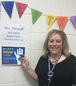 Mrs. Folcarelli poses with a 2019 NJSCA Bergen County Counselor of the Year poster in her honor