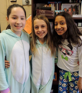 Three female students wearing pajamas pose together