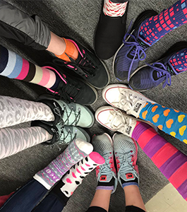 Students wearing patterned socks form their legs and feet in a circle